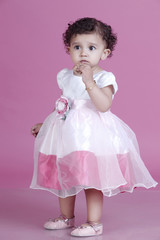 Full length of innocent girl eating cookie against pink background