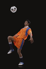 Happy male Indian soccer player doing kick ups isolated over black background © IndiaPix