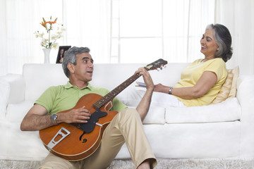 Husband playing the guitar while wife is listening