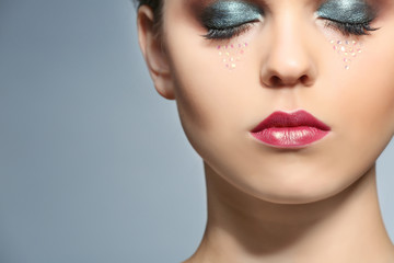 Fototapeta premium Beautiful young woman with creative makeup on color background, closeup