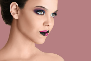 Fototapeta premium Beautiful young woman with creative makeup on color background