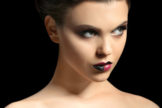 Beautiful young woman with creative makeup on dark background, closeup