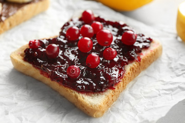 Tasty breakfast toasts with cranberry and jam on table