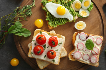 Fototapeta na wymiar Different tasty breakfast toasts with vegetables on table