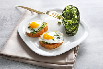 Tasty breakfast toasts with avocado and quail eggs on plate