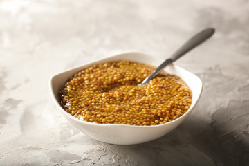 Bowl with delicious Dijon mustard sauce and spoon on table