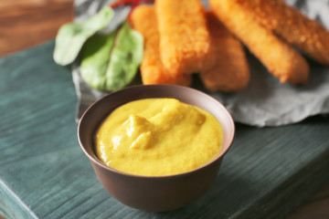 Gravy boat with delicious mustard sauce and nuggets on wooden board