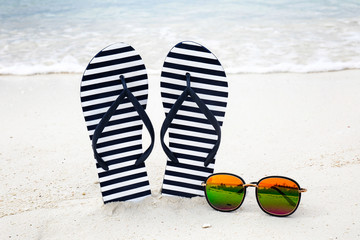 Flip-flops and sunglasses on beach sand. Summer vacation concept