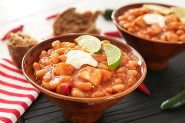 Bowl with delicious chili turkey on wooden board
