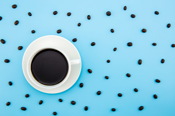 Stylish set: coffee beans on pastel and coffee cup blue background. Flat lay. Top view.
