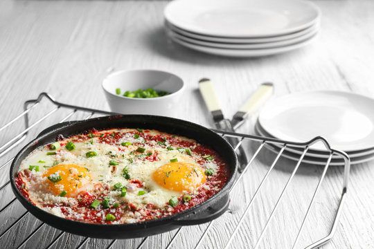 Frying pan with eggs in purgatory on table