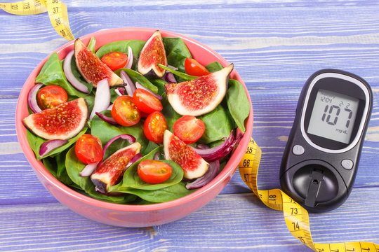 Fruit and vegetable salad and glucose meter with tape measure, concept of diabetes, slimming and healthy nutrition