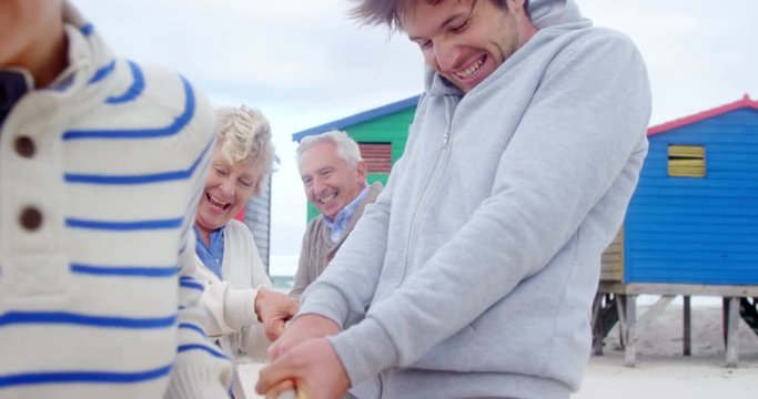 Multi generation family playing tug of war at beach