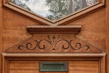 victorian oak exterior door detail with lace curtains and letter drop door