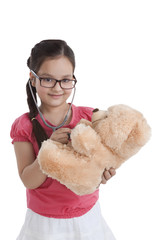 Portrait of little girl playing doctor with teddy bear