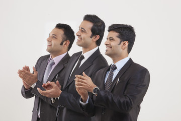 Businessmen clapping while watching cricket match 