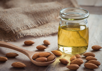 Almond oil in glass bottle and almonds on wooden table © ritablue