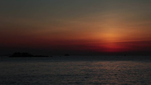 Sun coming up over the horizon with fishing boats and a tropical island looking out over the south China sea in Vietnam. High definition time lapse stock footage.
