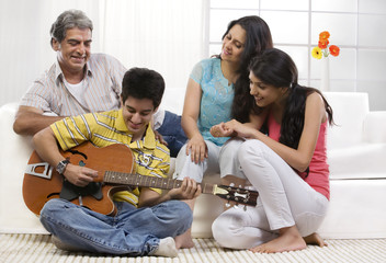 Boy playing the guitar for his family