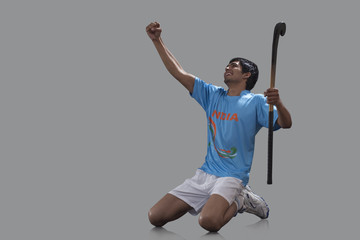 An excited Indian player with hockey stick celebrating success isolated over gray background