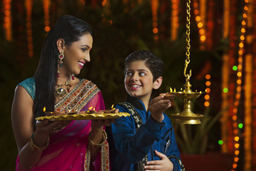Mother and son holding diyas