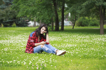 Young woman lying on the grass reading a message on a cell phone