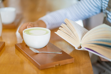 woman drinking coffee while reading book