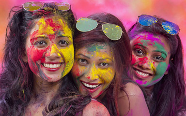 Portrait Of Three Young Indian Women With Colored Face celebrating Holi Color festival
