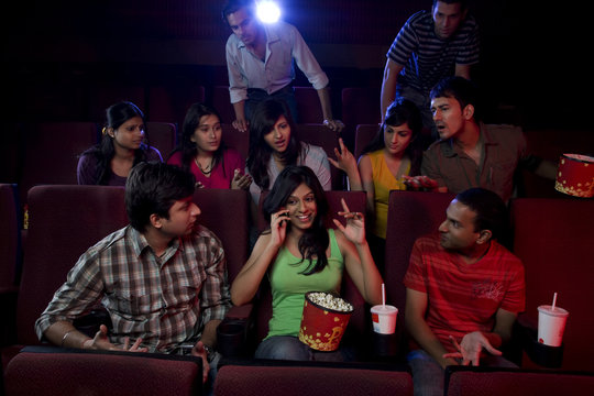 Girl talking on a mobile phone in a cinema hall 