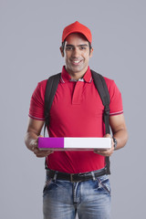 Portrait of confident pizza delivery man against gray background