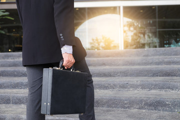 Businessman walking up the stairs and holding a briefcase in hand working with confidence