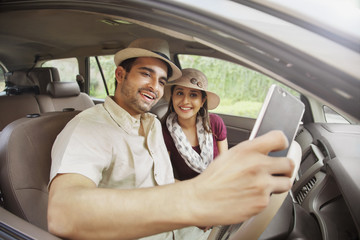 Couple wearing hat taking a selfie in car	