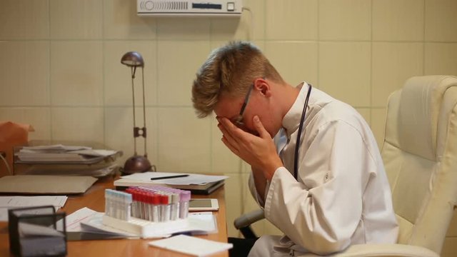 Doctor working on samples in the office and looks tired

