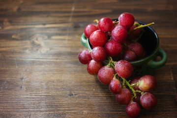 bunch of grapes on ceramic bowl over the wooden background