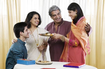 Girl offering sweets during Rakhi 