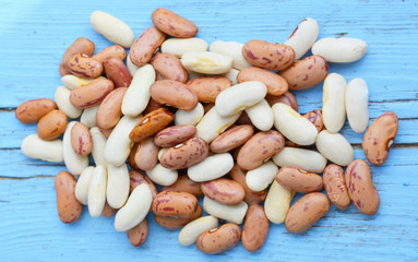 Beautiful composition: organic brown and white beans close-up isolated on blue wooden background, food