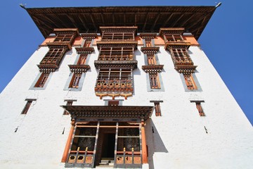 Traditional  Bhutanese style building decorated with carved wood window frames in Paro Rinpung Dzong, Buddhist monastery and fortress on a hill near the Paro Chu river. Paro, Bhutan.