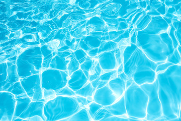 Blue and bright water surface and ripple wave with sun reflection in swimming pool