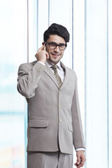 Portrait of young businessman answering smart phone in office