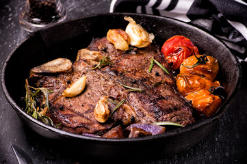Pan grilled large t-bone steak with garlic, tomatoes, herbs and seasoning.