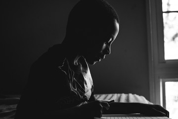 boy reads book quietly next to window 