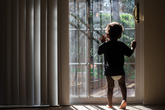 toddler  faces window to outdoors 
