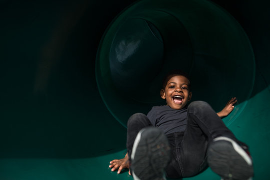 Boy laughing while playing on slide