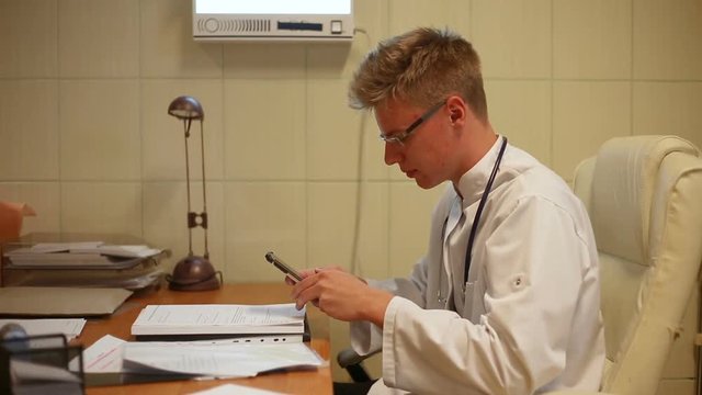 Doctor looks angry while texting messages on smartphone
