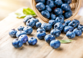 Freshly blueberries on wooden rustic wooden table. Juicy and fresh blueberries with green leaves. Bilberry on wooden background. Blueberry antioxidant. Concept for healthy eating and nutrition.