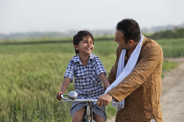 Obraz premium Man teaching son to ride bicycle 