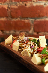 Pieces of cheese on a board with vegetables hd