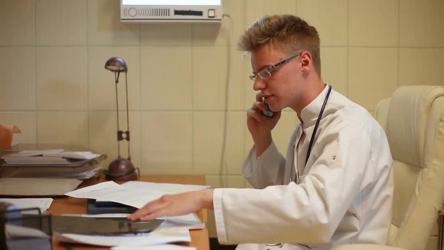 Doctor having problems with papers and arguing on cellphone in the office
