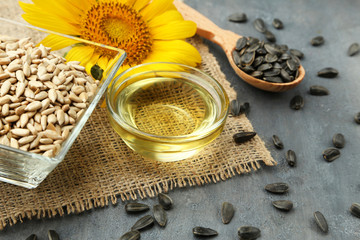 Sunflower seeds in bowl with oil on grey wooden table