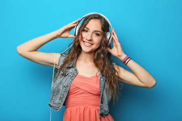 Portrait of young woman with headphones on blue background